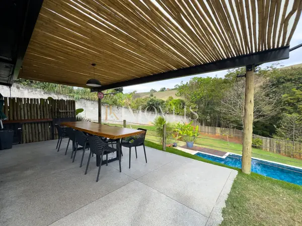 Área gourmet com pergolado, mesa e piscina na chácara em Campos Elísios
